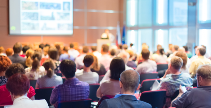 attendees at a conference listening to a speaker's presentation